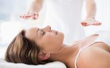 Midsection of therapist performing reiki treatment on woman