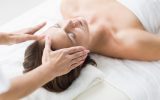 Cropped hands of therapist performing reiki on woman